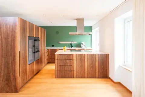 Eine Küche aus Nussbaum mit einer Kochinsel und Steinabdeckungen
