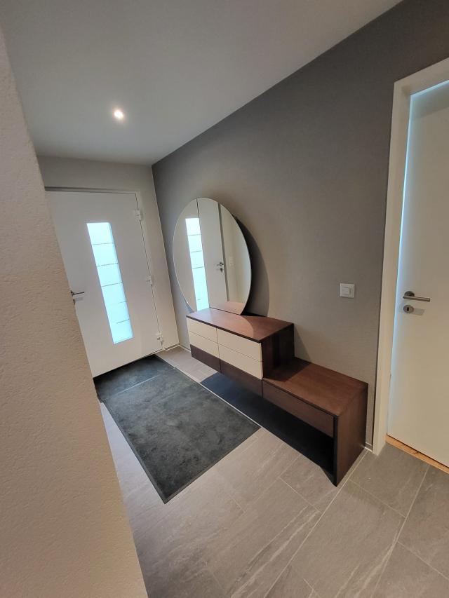 Möbel Entrée mit rundem Spiegel als Schlüsselschrank, rechts mit Sitzablage. Ausführung in Eiche furniert gebeizt, Schubladfronten lackiert nach RAL Farbton.