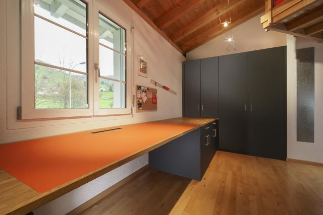 Grosse Arbeitsfläche mit integrierter Desktopablage und dunklem Einbauschrank