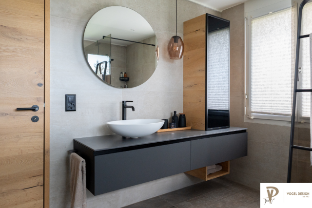 Badezimmer mit Holz und Kunstharz Oberflächen. Runder Spiegel und rundes Waschbecken.