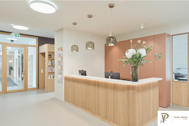 Heller Empfangsbereich mit Holzlamellen und eine grossen Blumenbouquet auf dem Tresen.