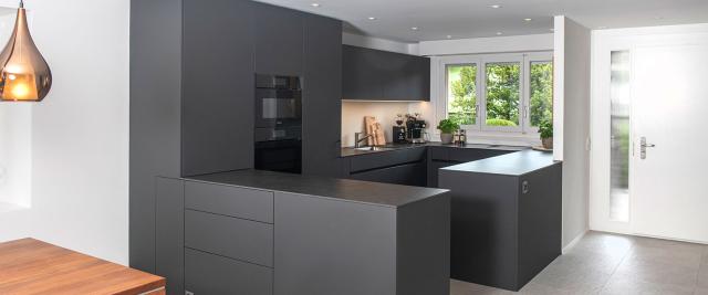 Küche mit mit eleganten schwarzen Fronten und einer hochwertigen Dekton-Abdeckung.