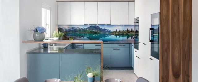 Moderne Schreinerküche in Blau und Weiss mit integrierter U-Form, Holzdetails und Schweizer Bergpanorama als Rückwand über der Arbeitsfläche